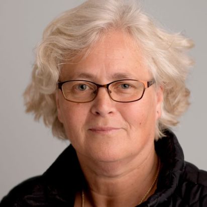 Nives Dolsak with a grey background posing for a headshot