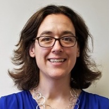 A headshot of Jennifer Hennessey is wearing glasses, a blue top, and a silver necklace of interlocking circles.