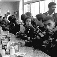 A group of African Americans sit at a counter in a diner to protest segregation laws