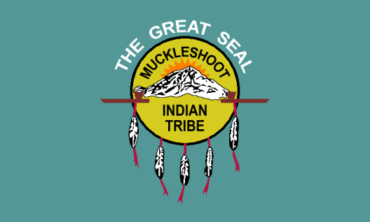 The Great Seal of the Muckleshoot Indian Tribe is depicted as a yellow circle encompassing Mount Rainer. Feathers line the outside of the circle.
