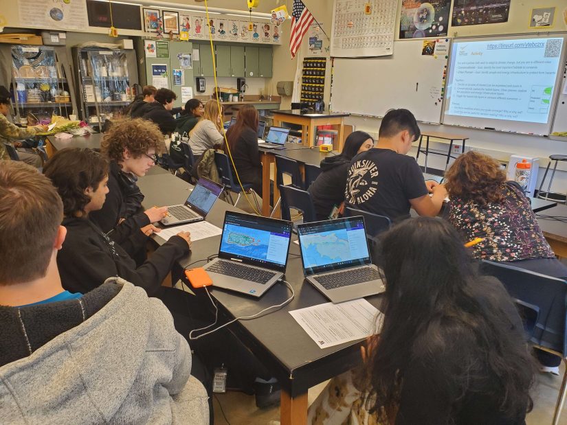 High school students working in pairs to explore the model on their laptops and fill out a worksheet.