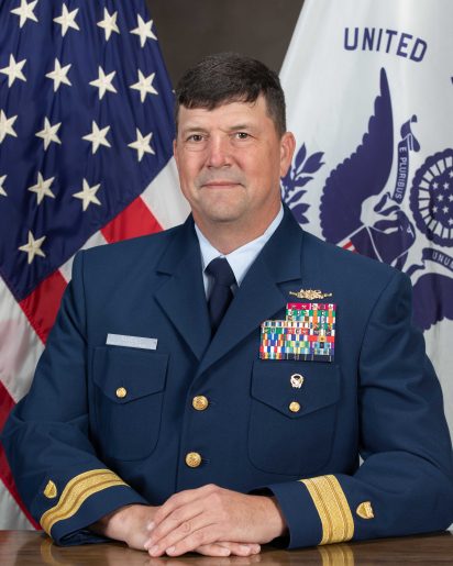 A uniformed military officer sits confidently, adorned with colorful medals. American and service flags drape behind, conveying honor and duty.