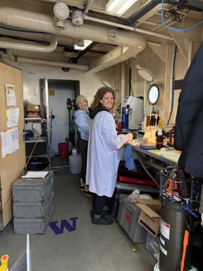 A laboratory bench with a setup for filtration. Multiple funnels and flasks are arranged in a line, with tubes connecting them. Nearby, there are various lab materials including test tubes, protective gloves, and bottles. The organization suggests meticulous scientific work.